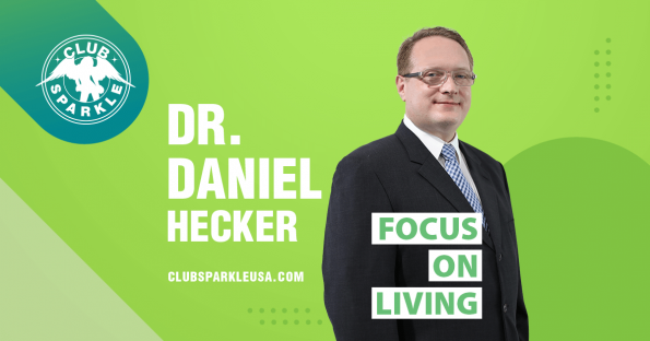 An image of Doctor Daniel Hecker wearing a black suit and white shirt with a blue tie with the words Focus on Living superimposed over him.