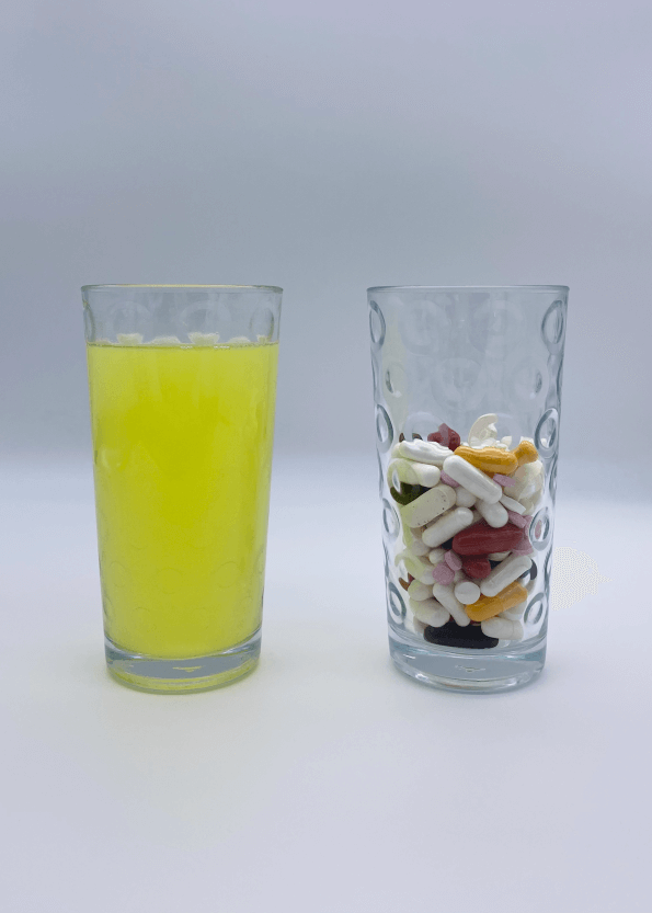 An image depicting a glass of EverYoung on the left and a glass halfway full of vitamin supplement pills. representing all of the pills you would have to take that can be replaced by EverYoung.